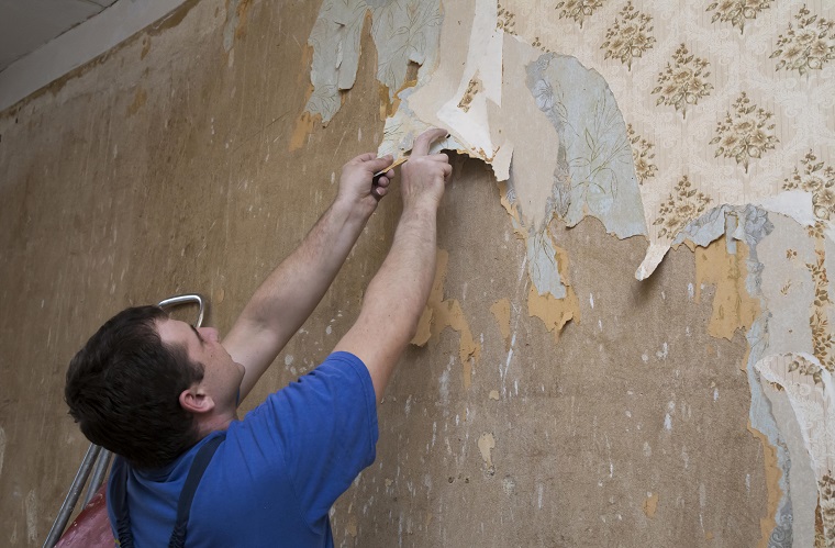 Tradesman is removing wallpaper